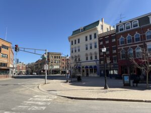Historic brick storefronts at the corner of Broad and Main streets in downtown Bangor, Maine on a clear spring day