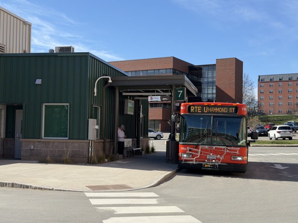 Community Connector bus displaying "RTE U Hammond St" parked at Bay 7 transit stop in Bangor, Maine on a sunny day.