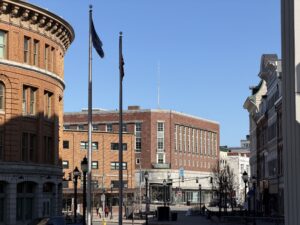Historic brick buildings and flagpoles along Main Street in downtown Bangor, Maine on a clear winter afternoon