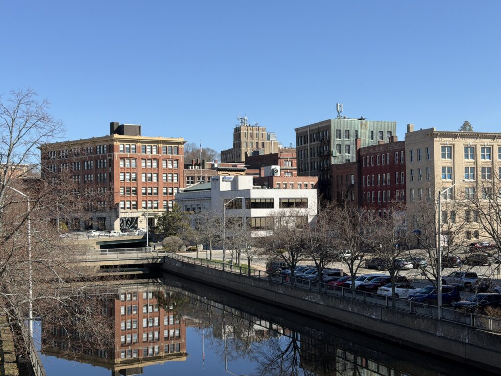 Historic brick buildings of downtown Bangor, Maine reflected in the Kenduskeag Stream on a clear spring day
