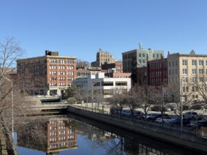 Historic brick buildings of downtown Bangor, Maine reflected in the Kenduskeag Stream on a clear spring day