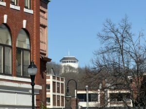 Thomas Hill Standpipe rising above downtown Bangor, Maine, framed by a historic red brick building and bare trees