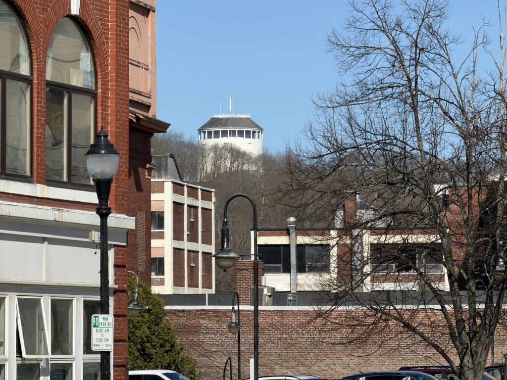 Thomas Hill Standpipe rising above downtown Bangor, Maine, viewed past brick storefronts on a clear winter day