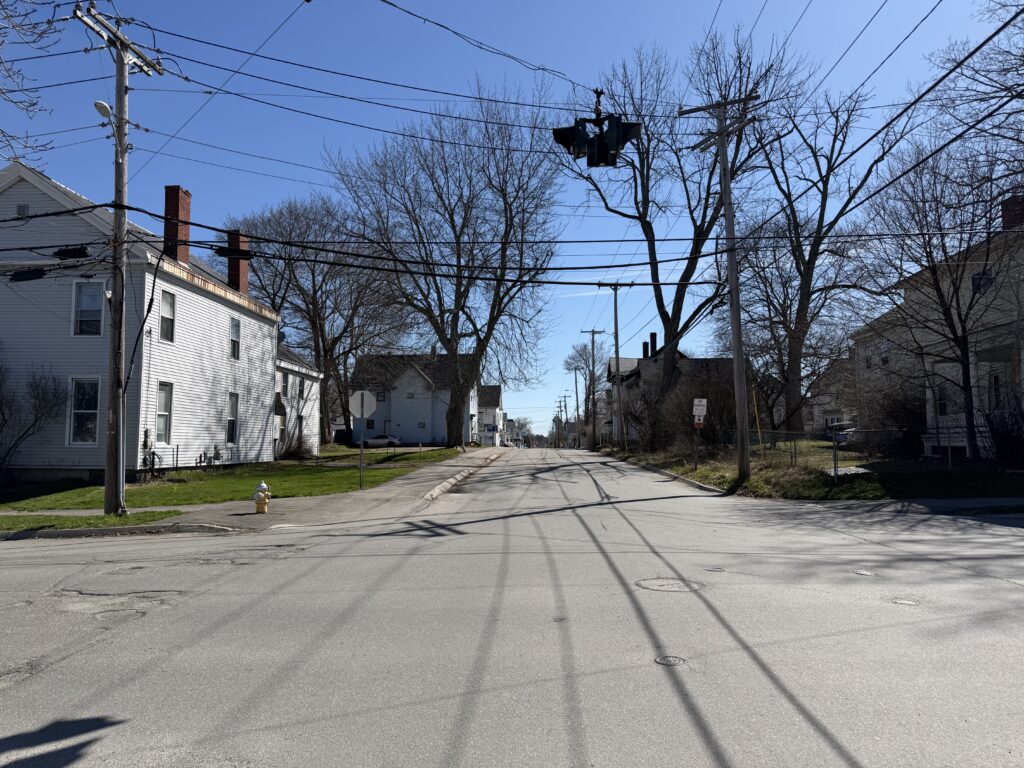 Quiet residential street in Bangor, Maine with bare trees and older New England homes in early spring