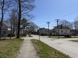 Quiet residential street in Bangor, Maine with New England homes and tree-lined sidewalk in early spring